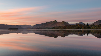 Fototapeta premium Pink and orange sunrise reflections at Derwentwater in the English Lake District.