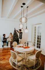 Young people decorate fir-tree for holidays of Christmas and New Year at home