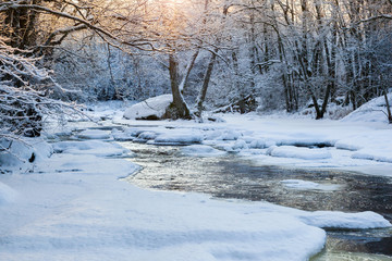 Sunset in the forest by the river with snow and ice
