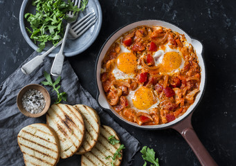 Coconut milk curry vegetables shakshuka and grilled bread on dark background, top view. Tasty comfort food
