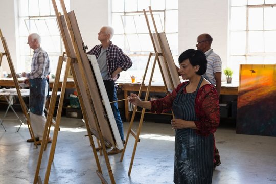 Senior male and female artists painting on easel