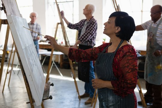 Senior female and male artists painting on easel