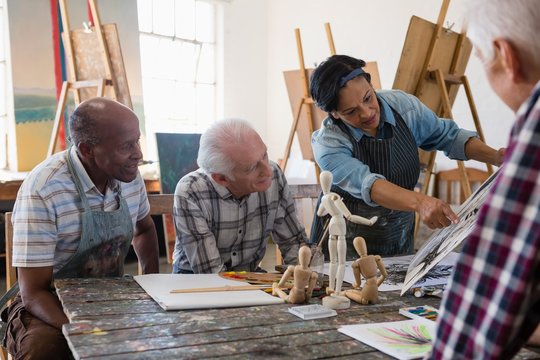 Senior woman showing painting to male friends