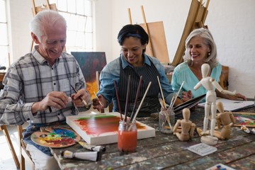 Happy senior artists painting in art class