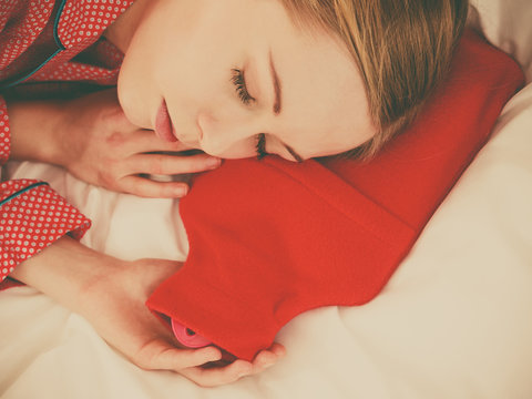 Woman sleeping with warm red hot water bottle