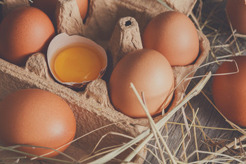 Fresh chicken brown eggs in carton on rustic wood background