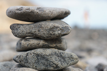 Fototapeta na wymiar Close-up of stack of stones in perfect balance on a tranquil sunny beach in Fuerteventura, SpainClose-up of stack of stones in perfect balance on a tranquil sunny beach in Fuerteventura, Spain
