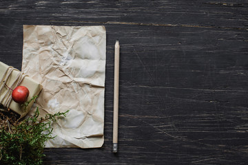 Sheet of paper on black wooden table with gift