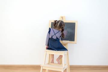 Cute little girl drawing on chalkboard at home.  Lifestyle Concept