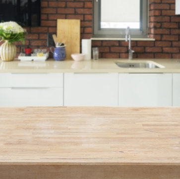 Empty kitchen wooden table top with white modern kitchen in background