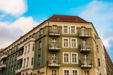 Fototapeta premium green and grey corner building with fluffy clouds in the background
