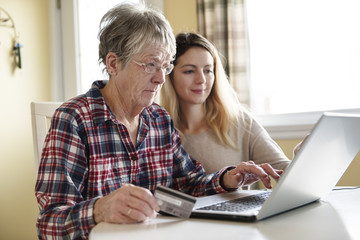 senior woman with her daughter online purchasing together
