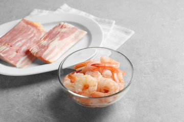 Composition with raw shrimps and bacon on table