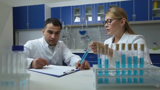 Confident scientists examining solution in lab