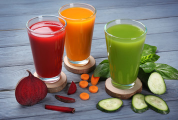 Glasses with various fresh juices and ingredients on table