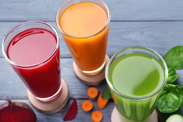 Glasses with various fresh juices and ingredients on table