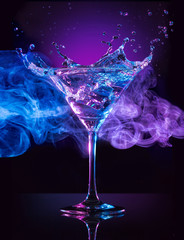 martini cocktail splashing on smoky blue and purple background © popout