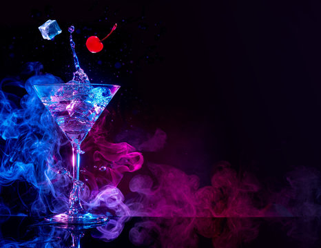 martini cocktail splashing in blue and purple smoky background