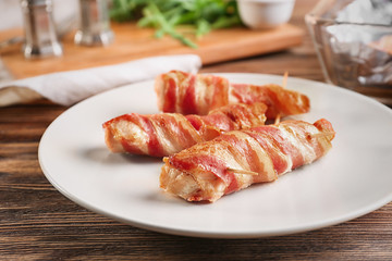 Plate with bacon wrapped chicken nuggets on table