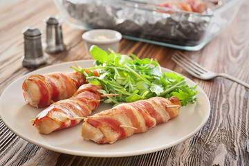 Plate with bacon wrapped chicken nuggets on table
