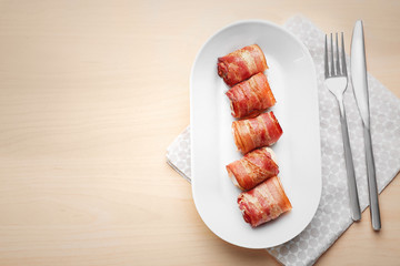 Ceramic plate with bacon wrapped chicken nuggets on table