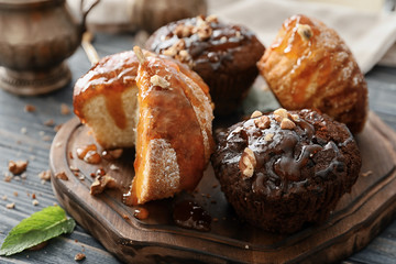 Board with tasty muffins and caramel topping on table