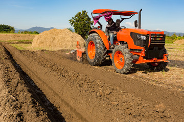 Obraz premium Tractor plows a field in the spring accompanied by Tractor