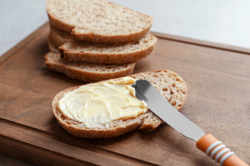 Slice of bread with butter on wooden board