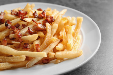 Plate with french fries and bacon on grey background