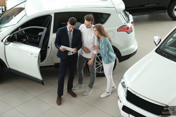 Young couple buying car in salon