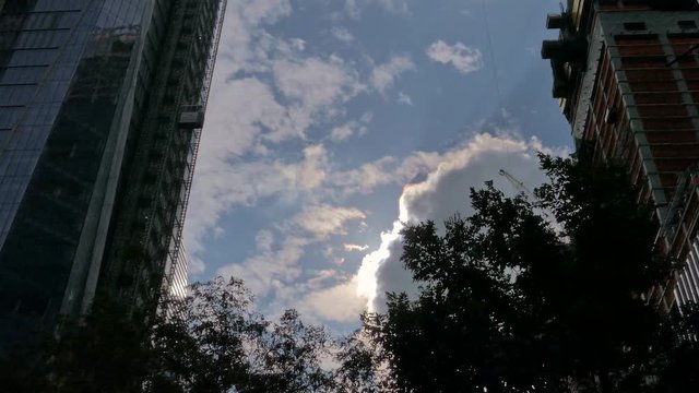 Sun appearing behind a cloud between two skyscrapers. A symbol of hope and renewal