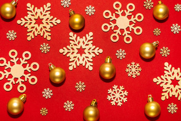 Fototapeta na wymiar Wooden snowflakes and gold New Year balls on a red background
