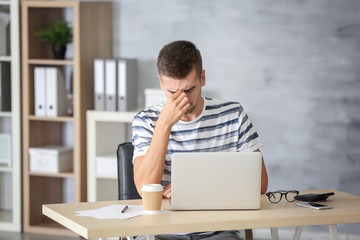 Tired man with laptop at home