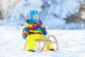 Boy on sleigh ride. Child sledding. Kid with sledge