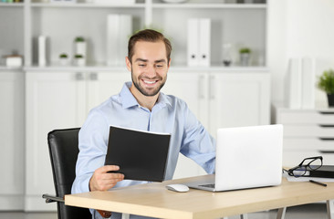 Attractive man with notebook and laptop in office
