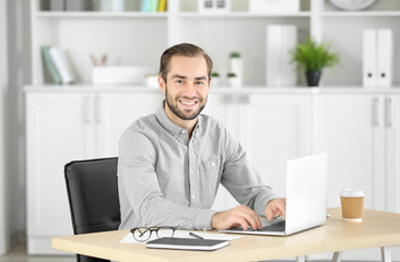 Fototapeta na wymiar Attractive man with laptop in office