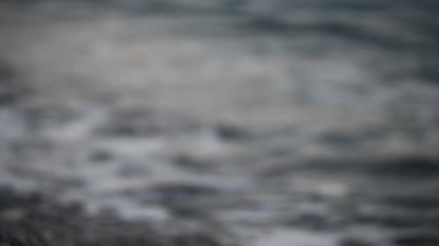 Particolare dell'onda che si infrange sulla battigia con piccoli sassi