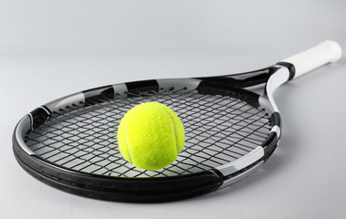 Tennis racket and ball on grey background