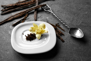 Composition with vanilla sticks, flower and seeds on table