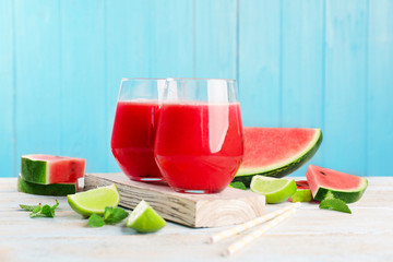 Glasses with fresh watermelon smoothie on table against blue wall