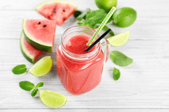Mason jar with fresh watermelon smoothie on wooden table