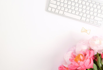 Feminine scene - workplace with keyboard and peonies, flat lay