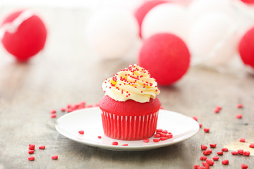 Plate with delicious red velvet cupcake on table