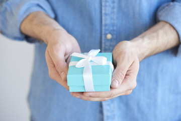 I want to give you a gift box. A man holding a present in his hands with wrapped with a bow.