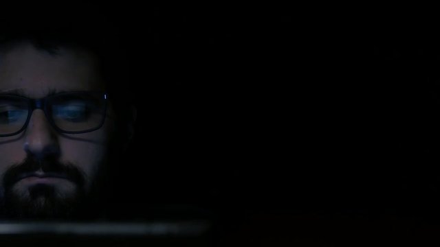 Reveal shot of hacker wearing glasses on laptop
