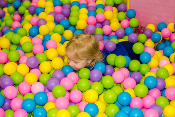 Fototapeta na wymiar little girl is playing in the pool with balls