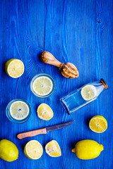Fresh homemade lemonade. Lemons, juicer, glass for beverage on blue wooden background top view copyspace