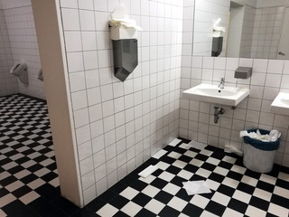 Handtuchspender mit Papierhandtüchern in einer öffentlichen Toilette mit Bodenfliesen im...