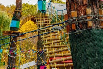  Alpinist adventure park in the autumn forest. Transitions from tree to tree on pendant wooden bridges.