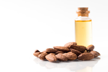 Bottle of almond oil and almonds isolated on white background